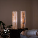 Illuminated alternate view of two 20-inch White Ice onyx cylinders with fine cream and amber vertical banding.