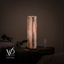 Illuminated alternate side of the White Ice onyx cylinder lamp with fine rippled bands and a smoky central seam.