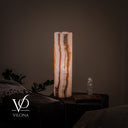 Illuminated side of the White Ice onyx table lamp with vertical cream, amber, and charcoal mineral bands.