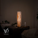 Wide illuminated view of the White Ice onyx lamp’s clouded side in a warm organic modern interior.