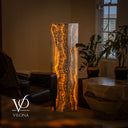 Golden Cloud onyx floor lamp glowing beside leather seating, indoor plants, and a sculptural natural stone table.