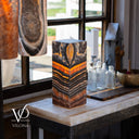 One-of-a-kind Tangerine Onyx table lamp glowing with orange, charcoal, cream, and brown natural banding