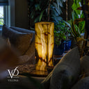 Illuminated Bamboo Onyx table lamp glowing in a plant-filled living room