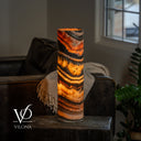 Tangerine Onyx cylinder lamp glowing with broad golden layers beneath diagonal orange and charcoal bands.