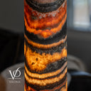 Close-up of illuminated Tangerine Onyx showing orange crystal formations, golden translucency, and dark charcoal bands.