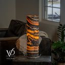 Illuminated Tangerine Onyx cylinder lamp with broad golden waves and sloping orange bands near the rim.