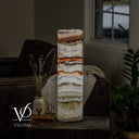 Illuminated Light Tangerine Onyx lamp with layered white stone, amber ribbons, and visible power cord at the base.