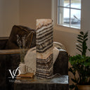 Unlit Tangerine Onyx cylinder lamp with diagonal cream and charcoal layers and a power cord extending to the right.
