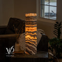 Illuminated Tangerine Onyx table lamp with golden bands, sweeping dark lower layers, and a visible inline cord switch.
