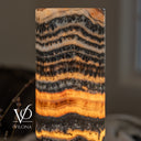Close-up of illuminated Tangerine Onyx showing fine charcoal ripples, branching mineral patterns, and a glowing orange band.