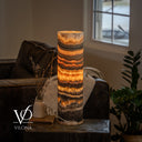 Cord-side view of a glowing Tangerine Onyx lamp with horizontal orange seams, golden crystals, and dark mineral bands.