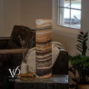 Unlit Tangerine Onyx lamp showing fine peach and taupe layers, larger cream crystals, and a dark brown band near the base.