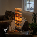 Illuminated Tangerine Onyx cylinder lamp with wavy amber bands, orange accents, and a power cord extending to the right.