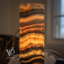 Close-up of illuminated Tangerine Onyx showing fine orange seams, broad golden crystals, and branching dark mineral details.