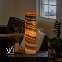 Illuminated Tangerine Onyx cylinder table lamp with charcoal waves, a golden crystal center, and layered orange ribbons.