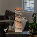 Unlit Tangerine Onyx cylinder lamp with dark upper bands, broad ivory crystals, and finely layered peach stone below.