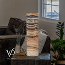Unlit Tangerine Onyx cylinder lamp showing wavy charcoal bands above cream crystals and fine apricot layers.
