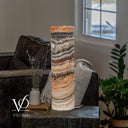Unlit Tangerine Onyx lamp with sweeping ivory and peach layers beneath charcoal banding and a cord to the right.