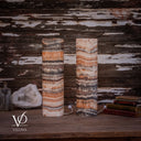 Unlit Tangerine Onyx cylinder lamp pair showing layered apricot stone, ivory crystals, and smoky-brown formations.