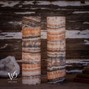 Closer unlit view of two Tangerine Onyx cylinder lamps with peach crystals, ivory waves, and mottled brown stone.