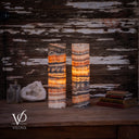 Tangerine Onyx lamp pair glowing on a wooden table beside a white geode, glass bottles, and stacked books.