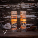 Tangerine Onyx cylinder table lamp pair illuminated, with golden amber bands, pale peach tops and charcoal veining.
