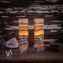 Illuminated Tangerine Onyx lamp pair with glowing amber centers and a sweeping ivory vein near the left lamp’s base.