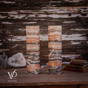 Unlit Tangerine Onyx lamp pair from a third angle, showing peach bands and diagonal cream veining through charcoal stone.
