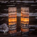 Closer view of illuminated Tangerine Onyx lamp pair, showing golden crystalline bands framed by charcoal and reddish-brown stone.