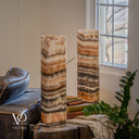 Unlit Tangerine Onyx lamp pair with the rear lamp in focus, showing peach and ivory layers above dark mottled stone.