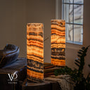 Illuminated Tangerine Onyx cylinders with curved cream bands near the front lamp’s rim and orange crystalline layers.