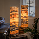Closer illuminated view of Tangerine Onyx lamp pair, showing the front lamp’s open rim, amber bands and charcoal formations.