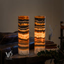 Tangerine Onyx table lamp pair illuminated, with glowing amber centers, dark upper bands and pale ivory bases.