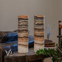 Unlit Tangerine Onyx lamp pair showing irregular charcoal bands, broad cream crystals and fine tan and peach layers.