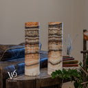 Unlit Tangerine Onyx cylinder lamp pair showing a rounded ivory crystal formation and curved bands on the right lamp.