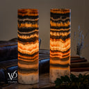 Closer illuminated view of Tangerine Onyx lamp pair, showing amber crystal bands and branching dark markings in the upper stone.