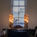 Illuminated Tangerine Onyx lamp pair with amber bands sloping downward to the right and deep charcoal curves near the bases.