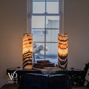 Illuminated Tangerine Onyx lamps showing cord exits, glowing crystal layers, and a dark V-shaped band on the right lamp.