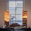 Illuminated Tangerine Onyx lamp pair with broad amber crystal bands and sweeping charcoal curves, styled on a console.