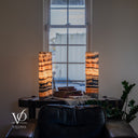 Illuminated Tangerine Onyx lamps with curved dark bands around a pale formation on the left and straighter horizontal layers on the right.