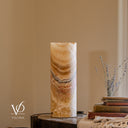 Unlit Aqua Onyx cylinder lamp showing ivory and honey tones, curved charcoal outlines, pale rose bands, and a live-edge rim.