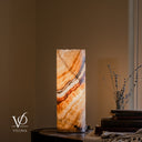 Illuminated Aqua Onyx lamp with layered ivory, charcoal, and salmon bands rising diagonally across its glowing crystalline body.