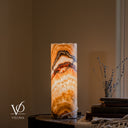 Rear view of an illuminated Aqua Onyx lamp with nested amber and charcoal arches and a white cord crossing the lower body.