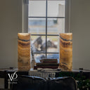 Unlit Aqua Onyx cylinder lamp pair with honey, cream, and smoky gray bands, smooth rims, and darker marbling near the bases.