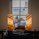 Illuminated Aqua Onyx lamp pair with upper bands sloping toward the center, glowing cream layers, and dark formations below.