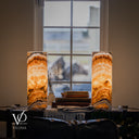 Illuminated Aqua Onyx lamp pair viewed from the cord side, showing charcoal-edged arches near the bases and amber crystal layers.