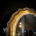 Decorative mirror with agate-like frame in a dark setting, featuring the brand 'Vilona'.