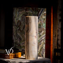 Decorative cylindrical vase with a marbled pattern on a dark surface, with 'Vilona' branding visible.