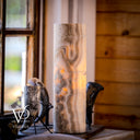 Decorative cylindrical lamp with marble-like pattern on a wooden surface, blurred background