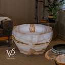 Illuminated White Ice Onyx coffee table with faceted sides, a tapered base, and honey-gold bands through white stone.